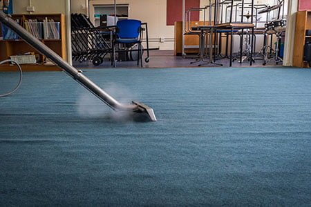 person steam cleaning a carpeted office